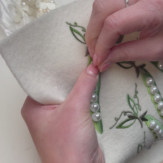 Pearls being hand sewn to the peapods