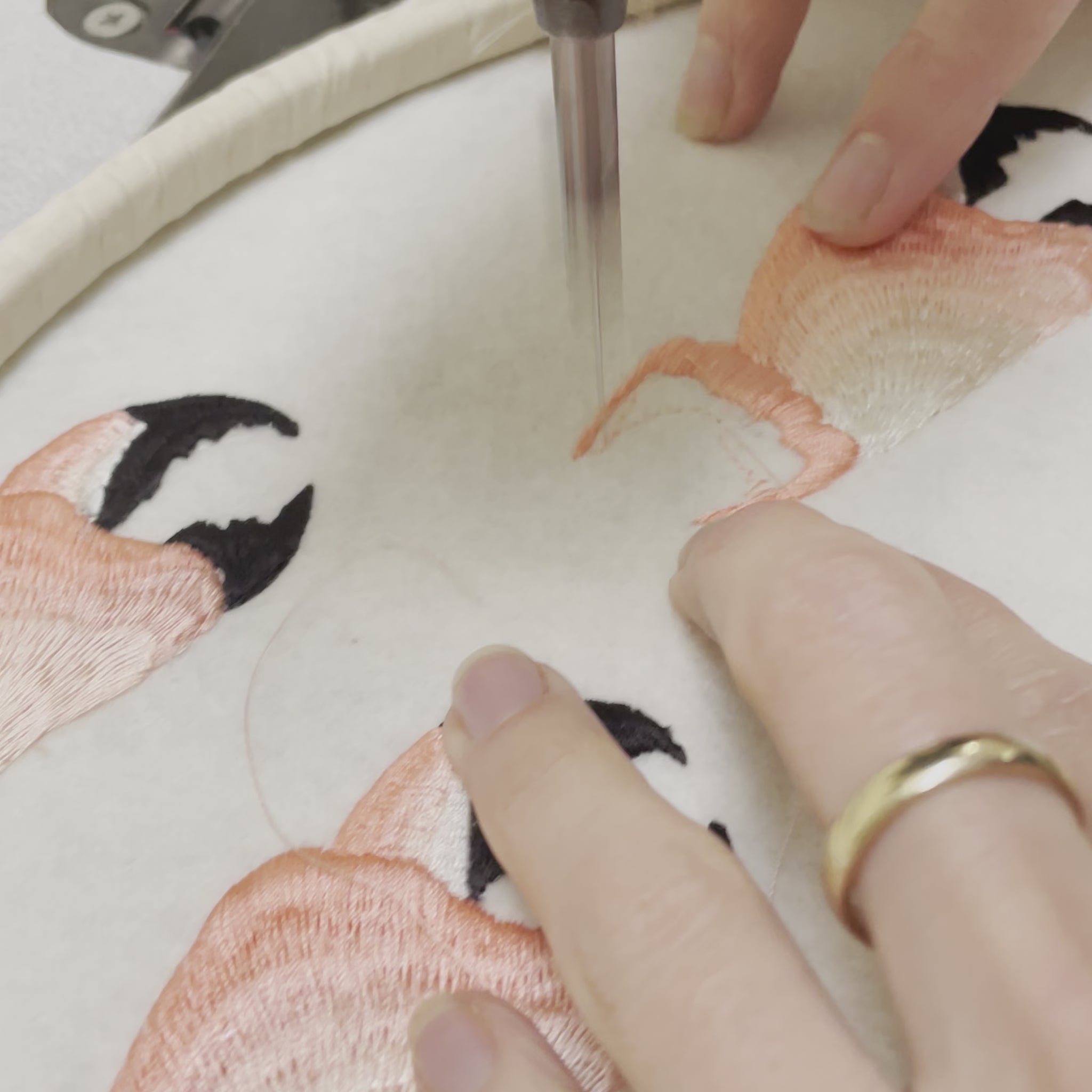 A close-up video of some hands and the needle of a sewing machine showing the embroidering of the crab claw