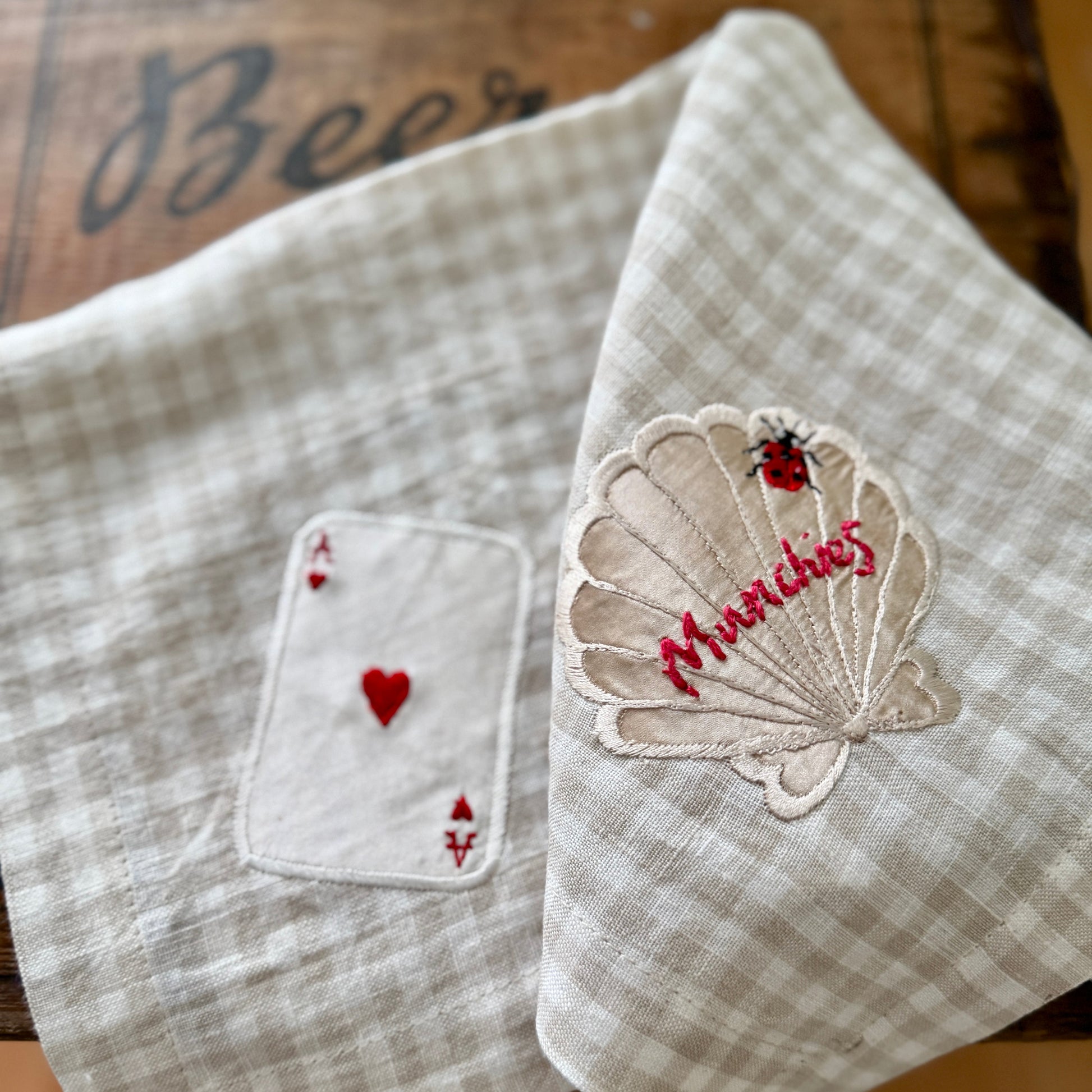 Two embroidered fabric napkins on a wooden surface