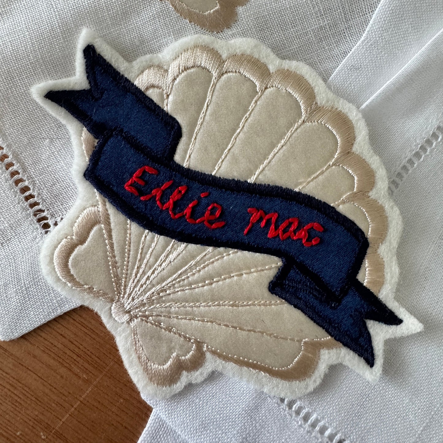 Embroidered patch with 'Ellie Mac' text on a scalloped edge background