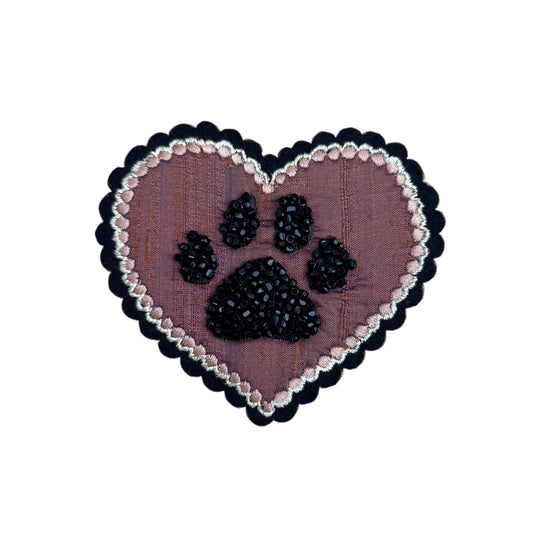 Heart-shaped patch with beaded paw print design on a white background