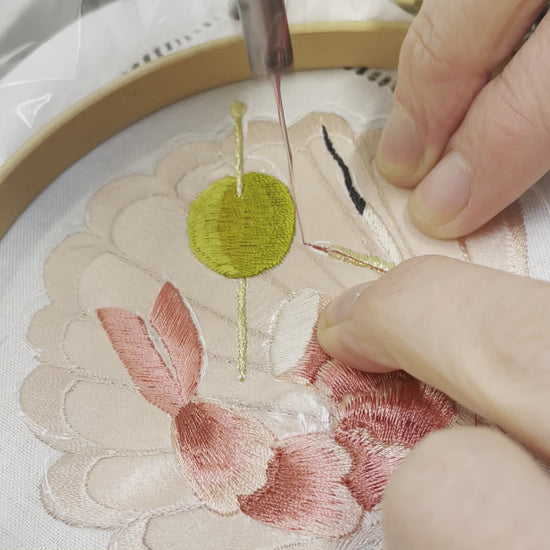 Video of Ellie Mac Embroidery, close-up of hands and machine needle and showing the embroidery on the head of a match. Embroidered olive and prawn tail also visible