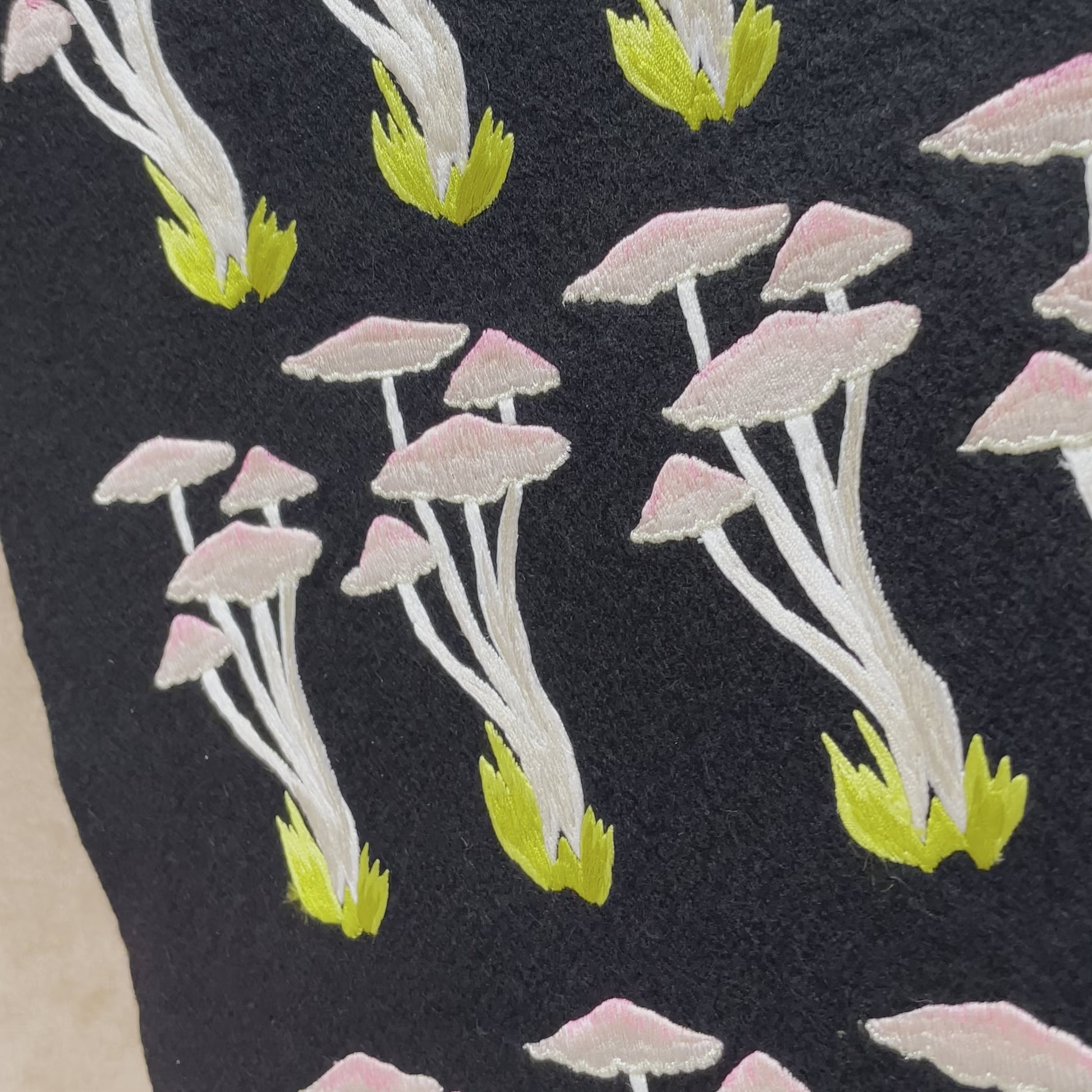 video of woodland mushroom embroidered patches on black felt before being cut out