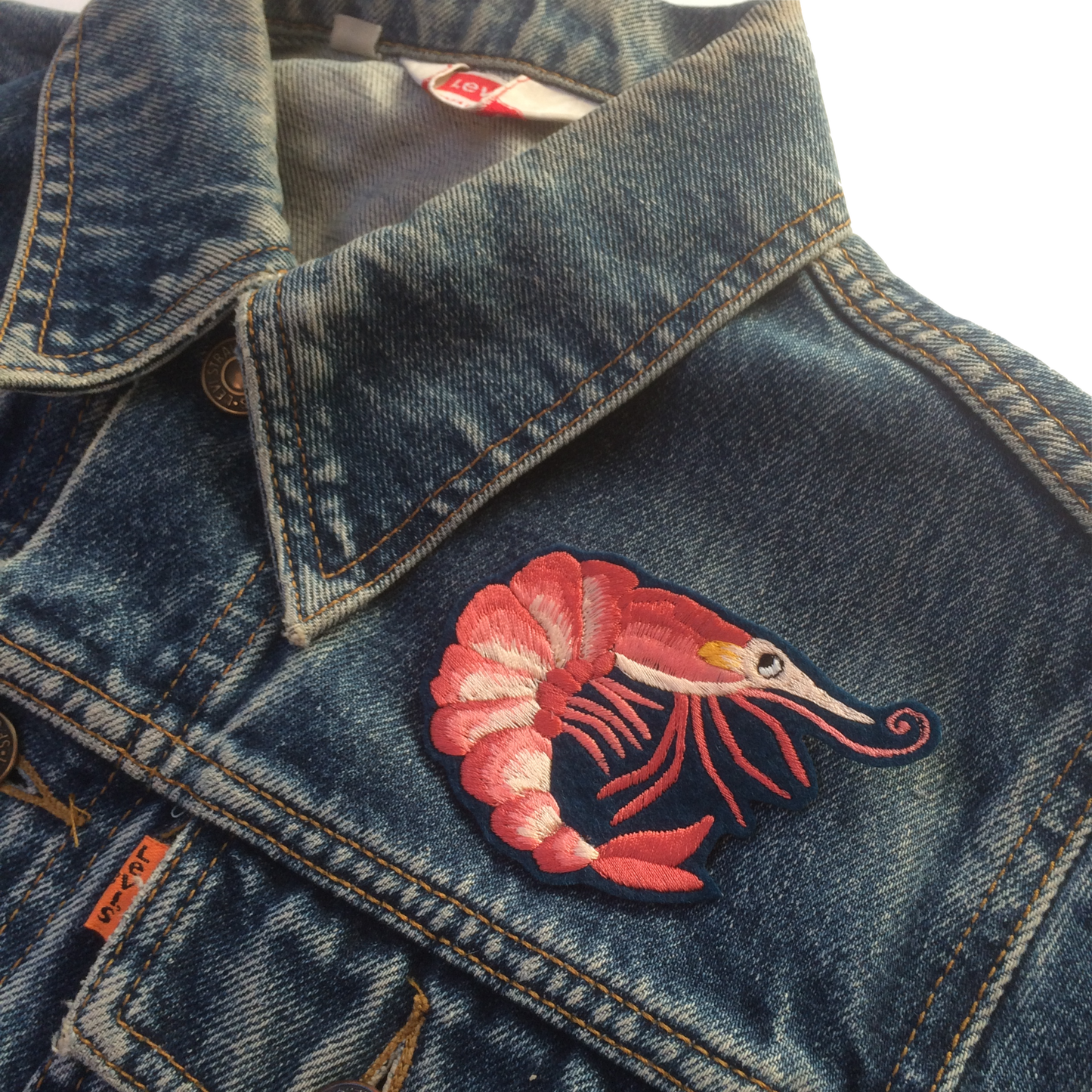 Prawn embroidered patch shown on the front shoulder of a denim jacket