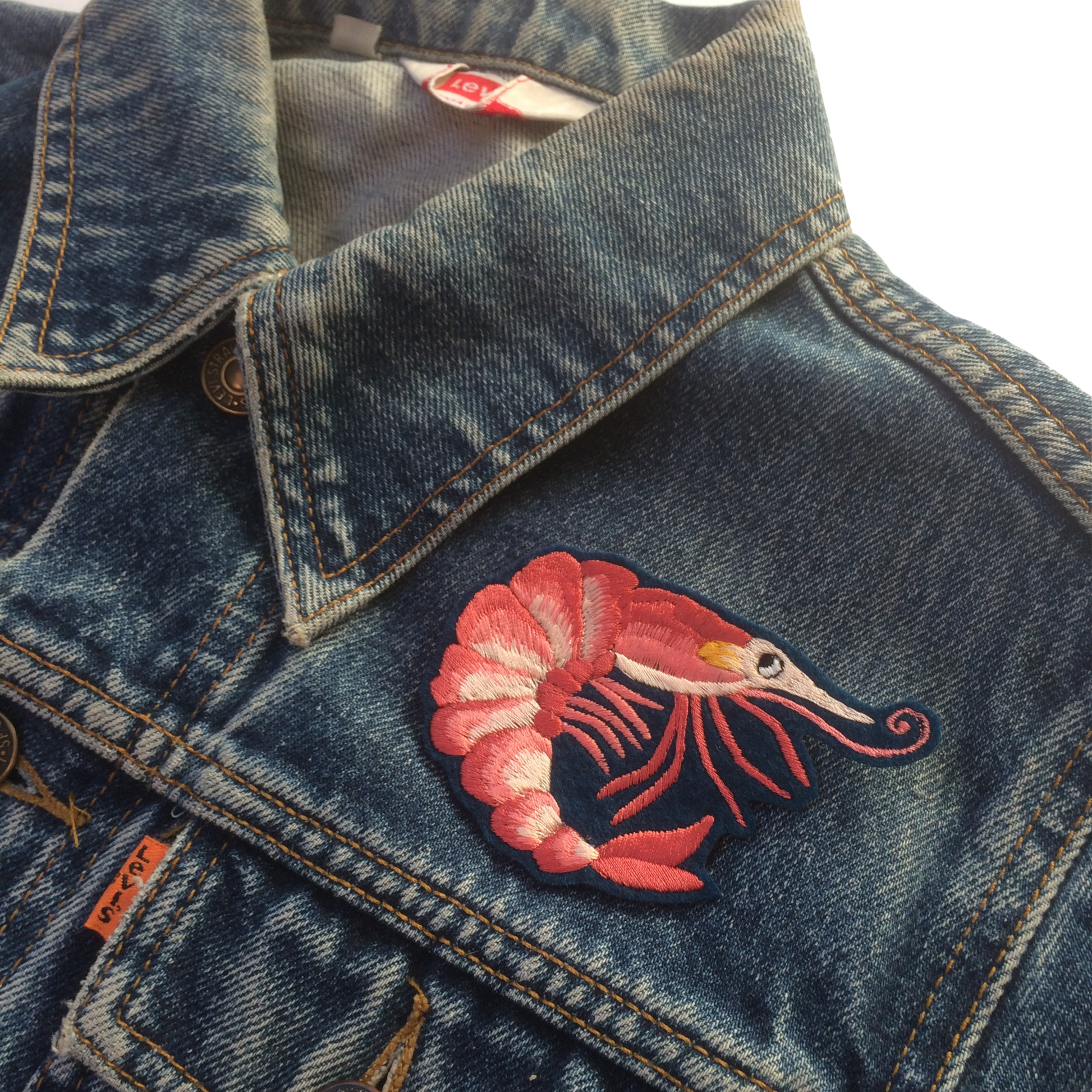 Prawn embroidered patch shown on the front shoulder of a denim jacket