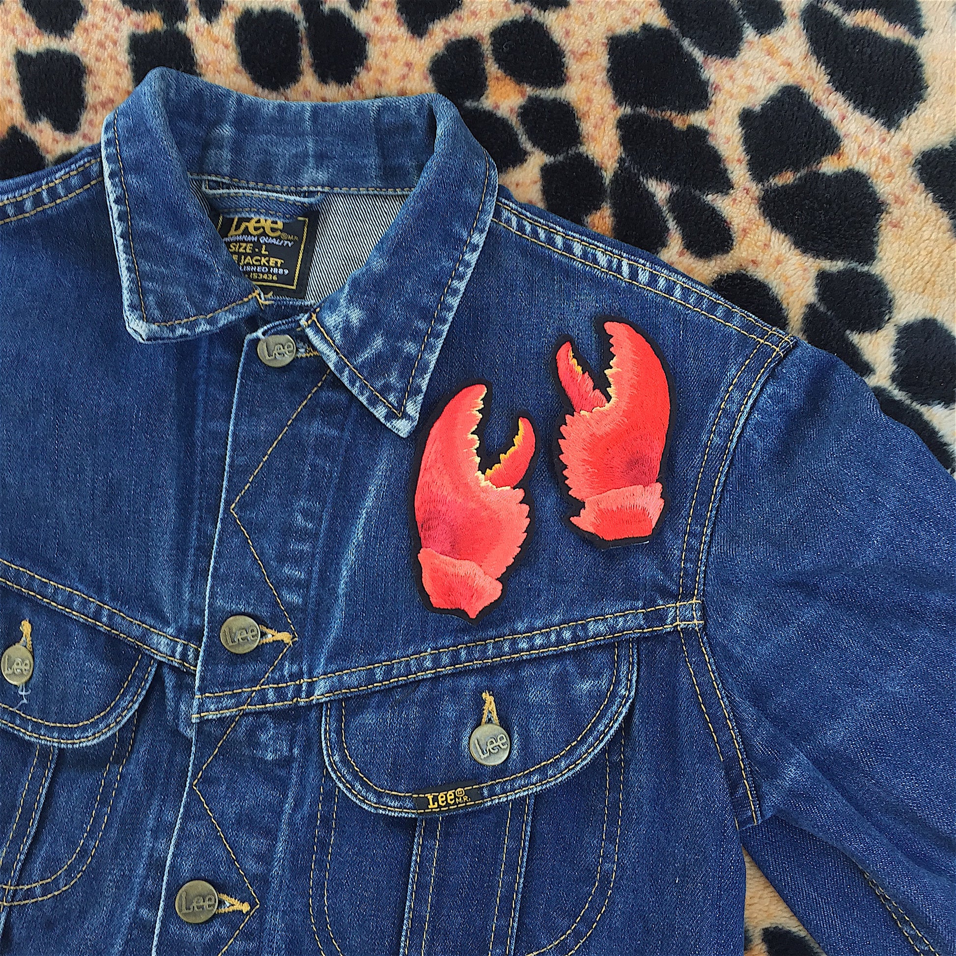 Pair of lobster claw embroidered patches shown on the front breast of a denim jacket