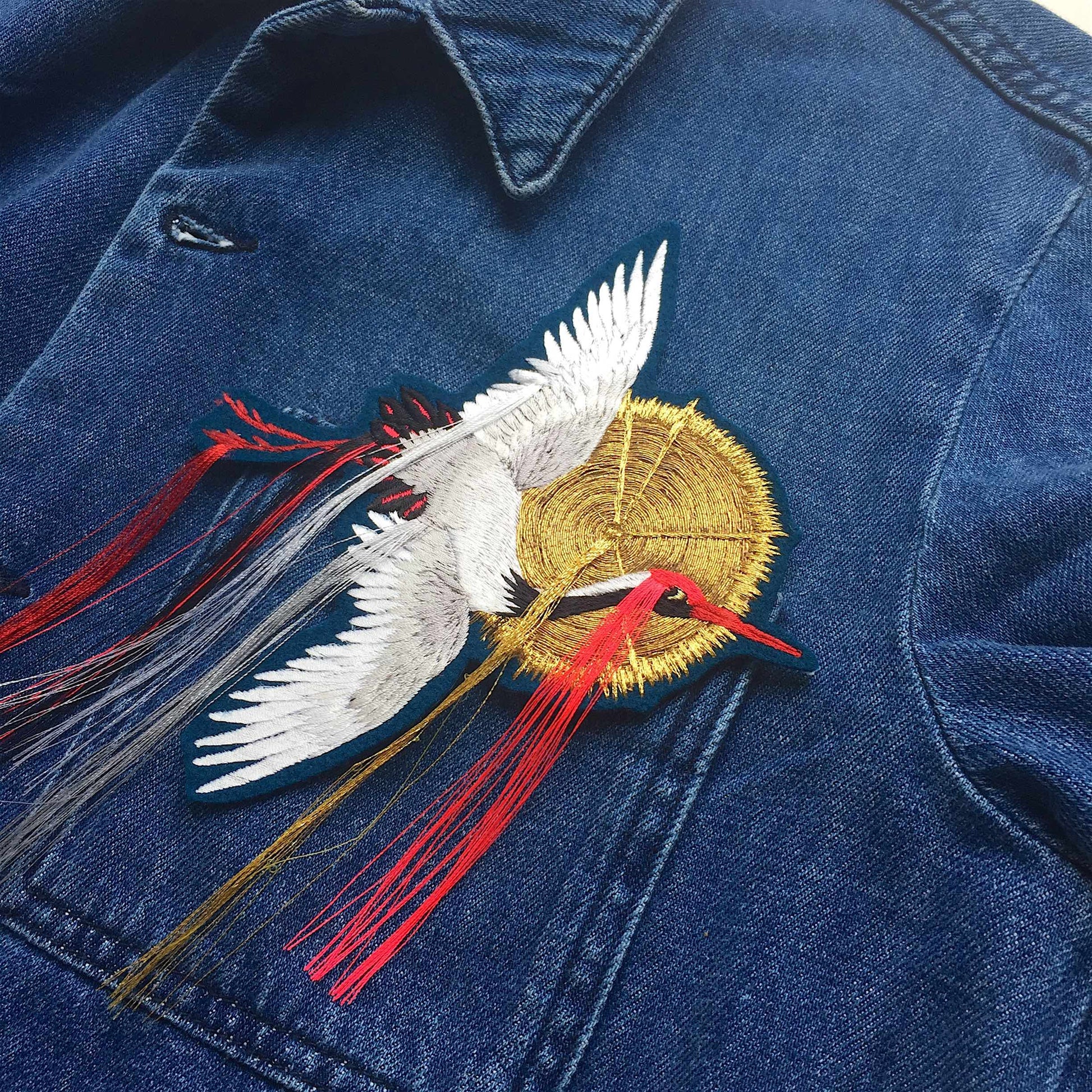 Fringed Crane Embroidered Patch shown on the front pocket of a denim overshirt