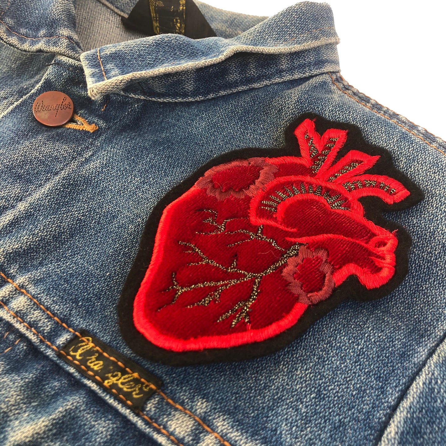 Close-up of velvet heart embroidered patch on blue denim jacket