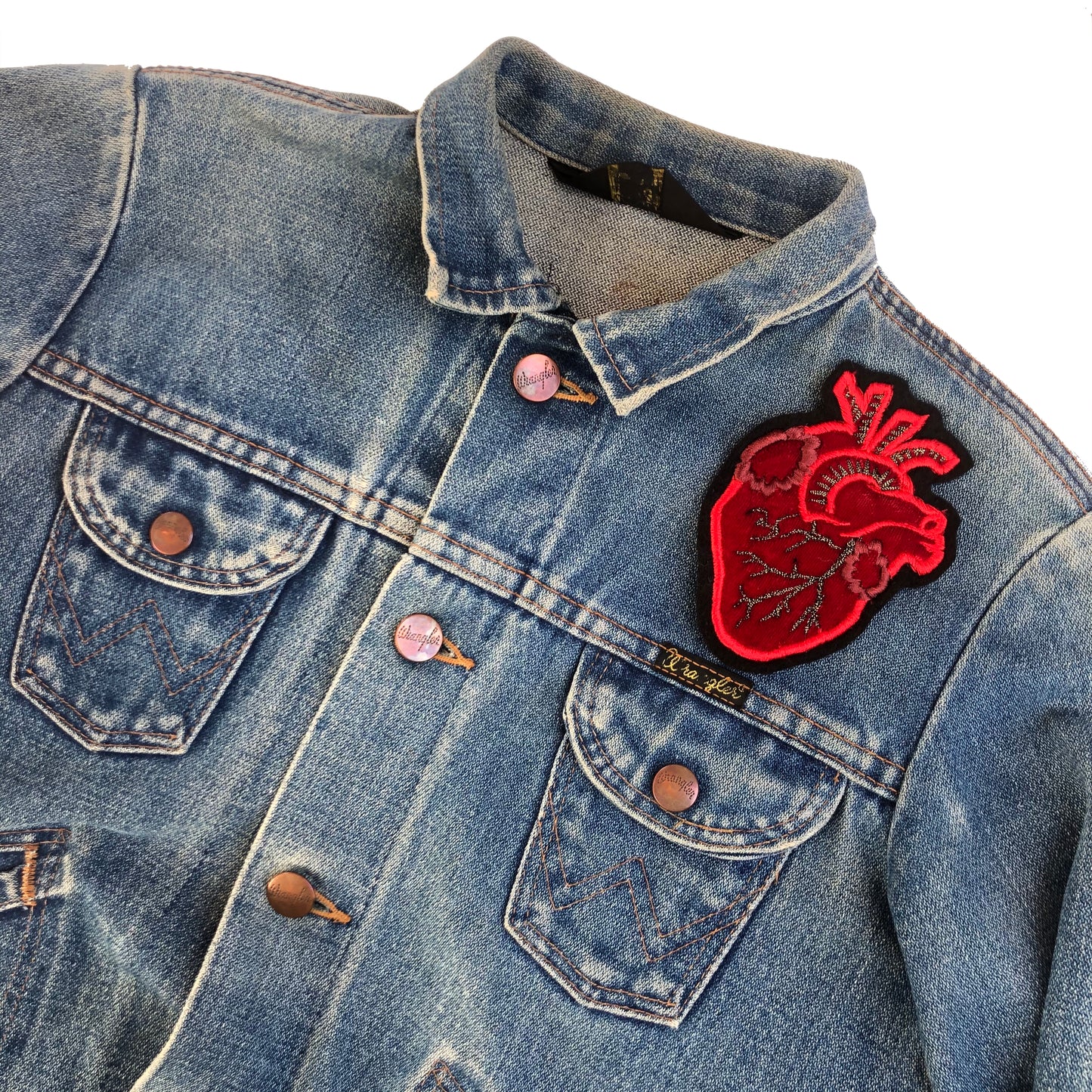 Velvet heart embroidered patch on the front shoulder of a blue denim jacket