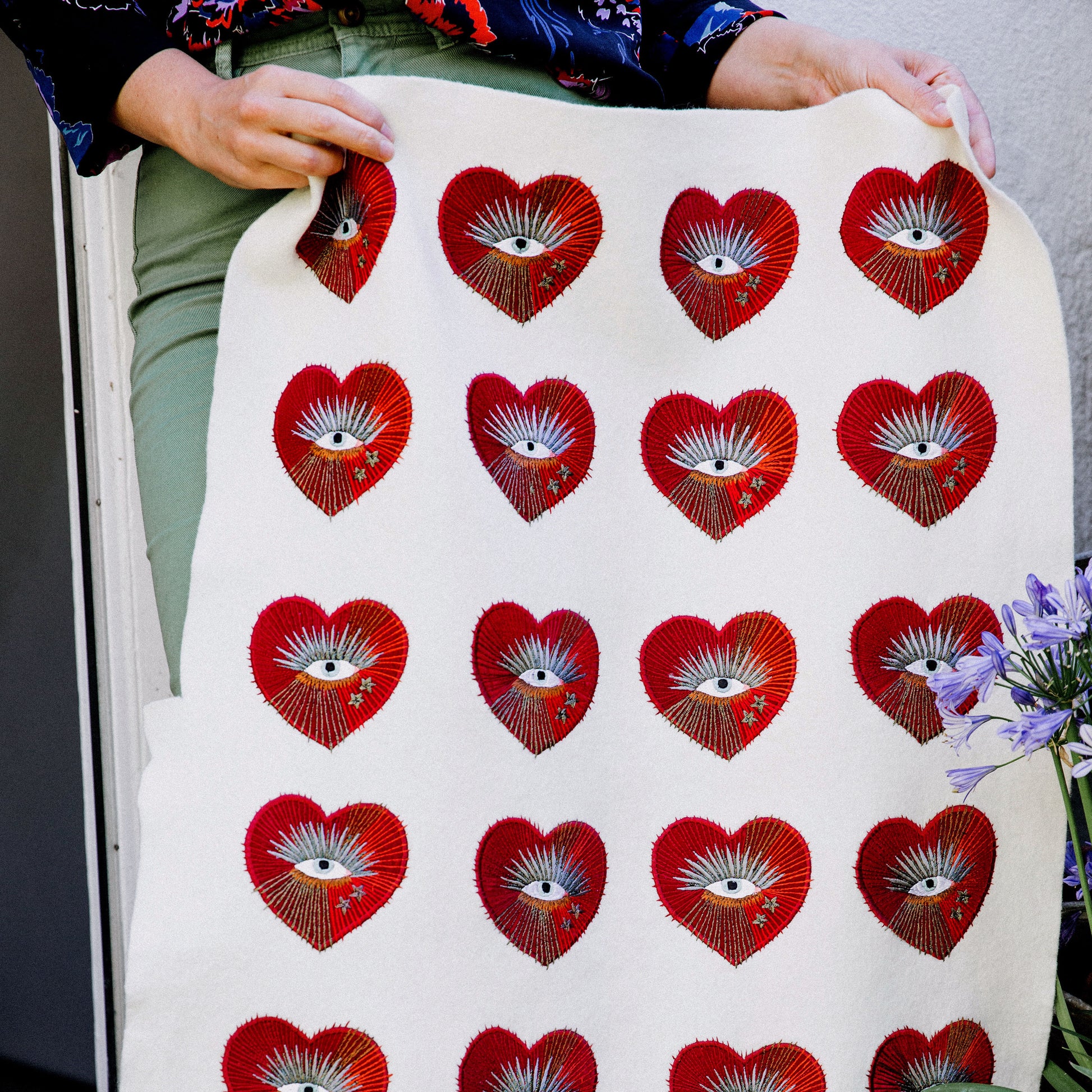 A selection of pre-cut sacred heart with eye embroidered patches held up by two hands