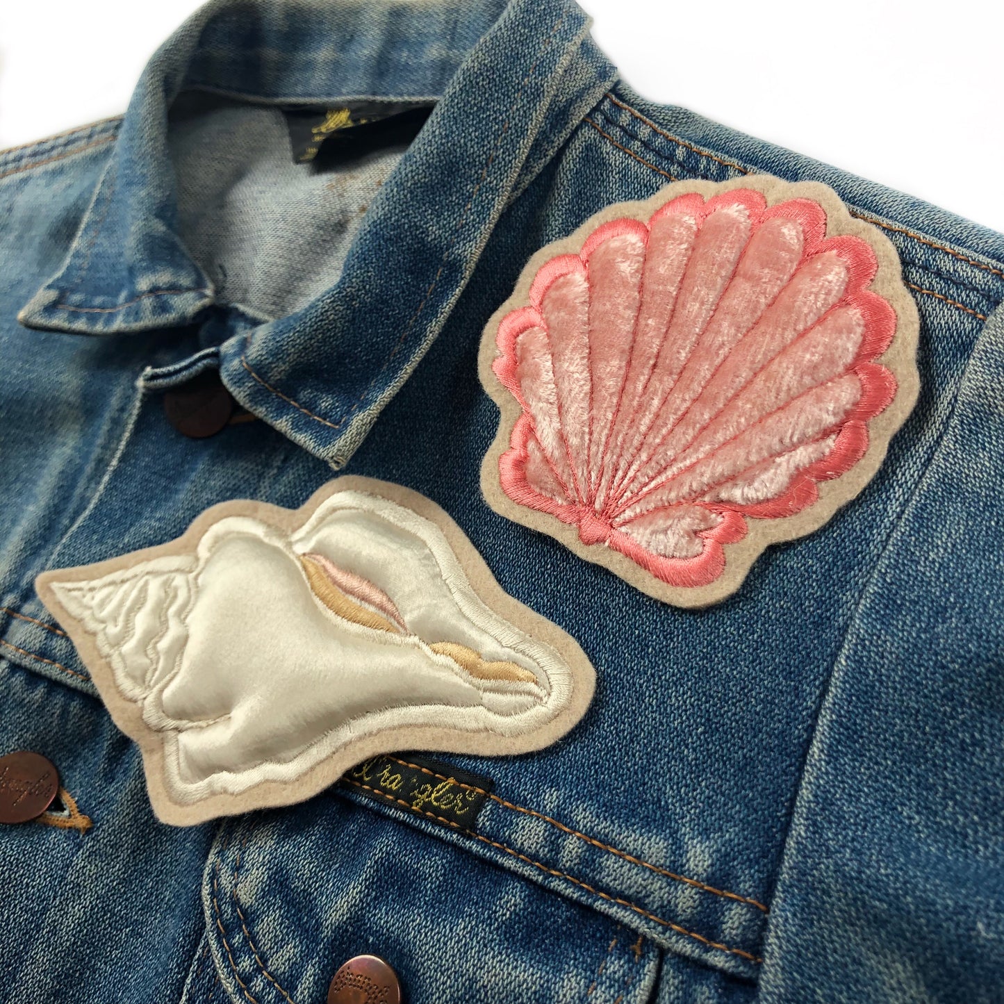 Padded velvet clam patch and white satin conch patch on front breast of a denim jacket