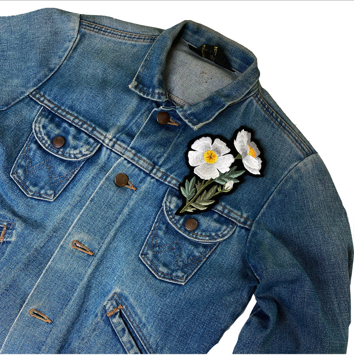 Fried egg flower embroidered patch on front shoulder of a denim jacket