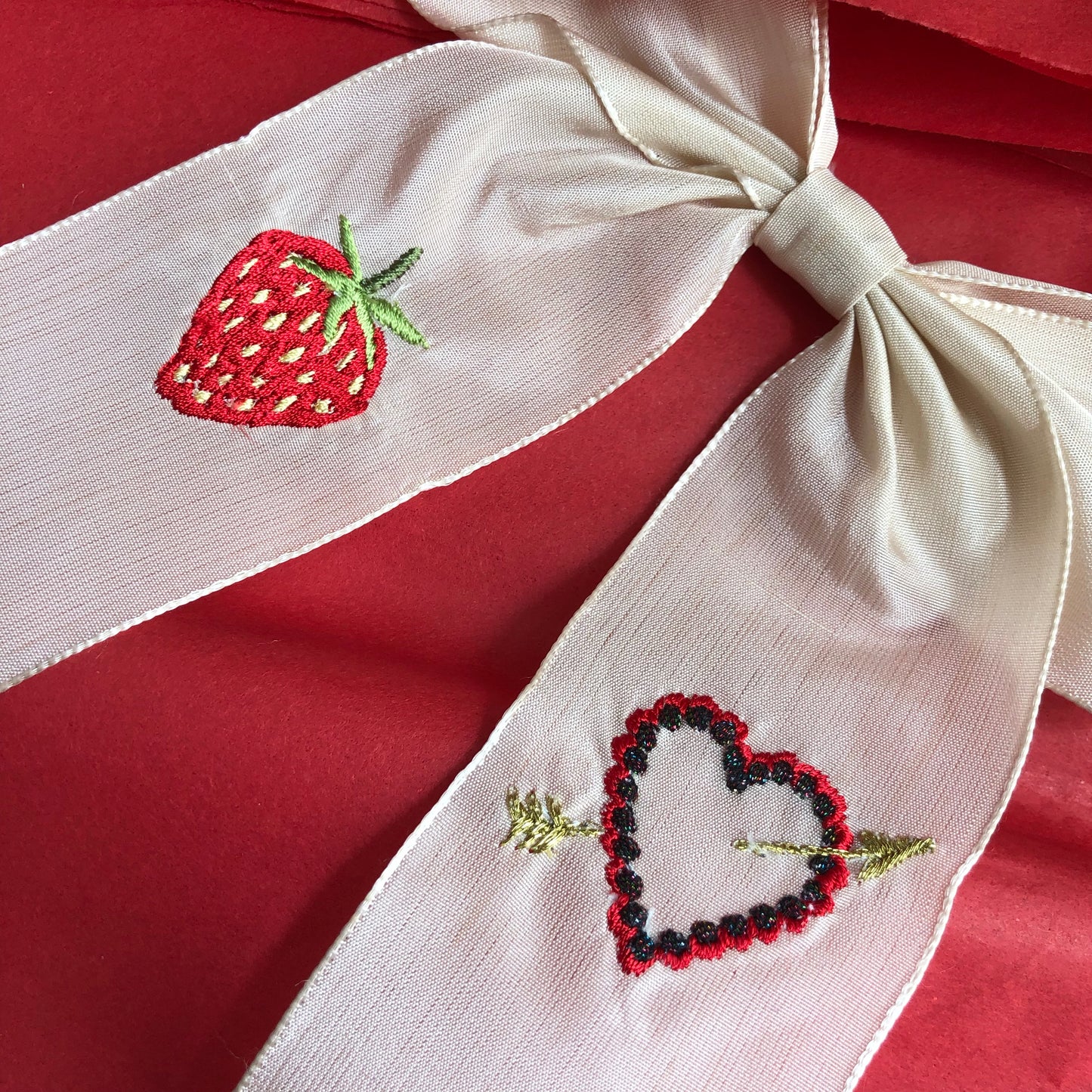 Close-up of vintage ribbon strawberry hair bow on deep red tissue