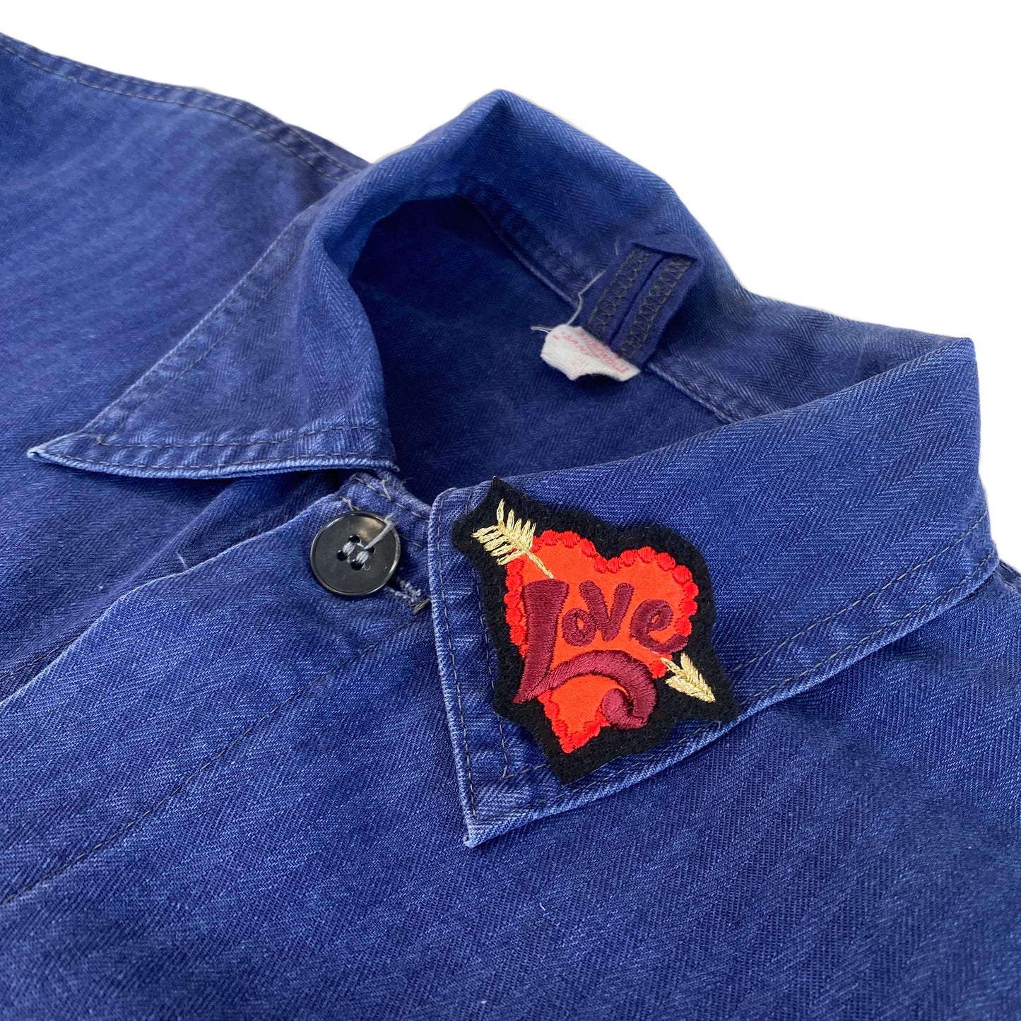 Tiny love embroidered patch shown on collar of blue jacket