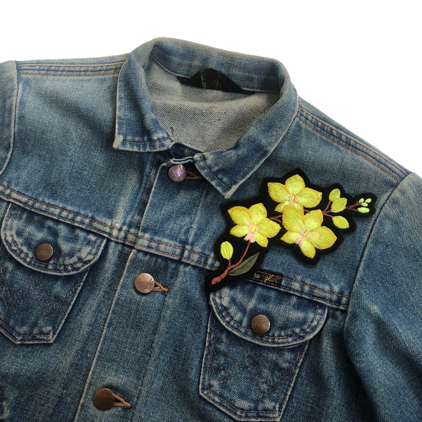 Orchid embroidered patch on front shoulder of blue denim jacket