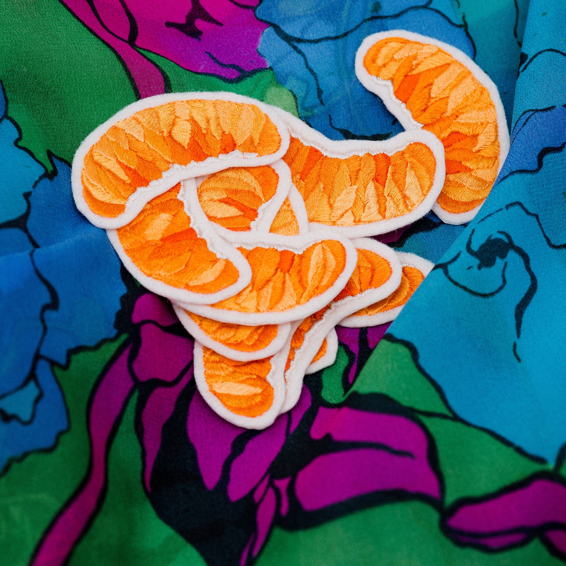 Collection of orange slice embroidered patches on a patterened background