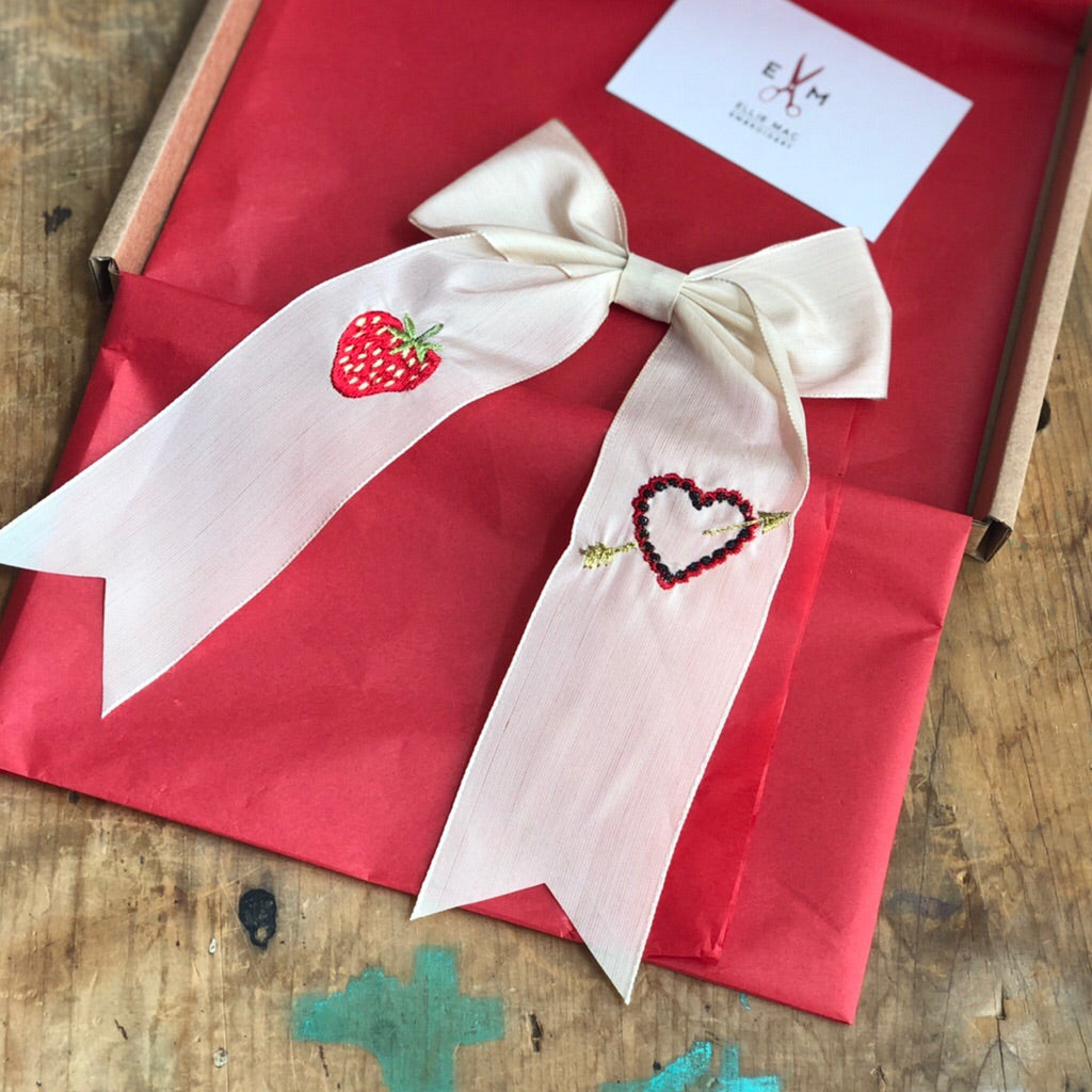 Vintage ribbon strawberry hair bow lain on deep red tissue paper on a wooden table