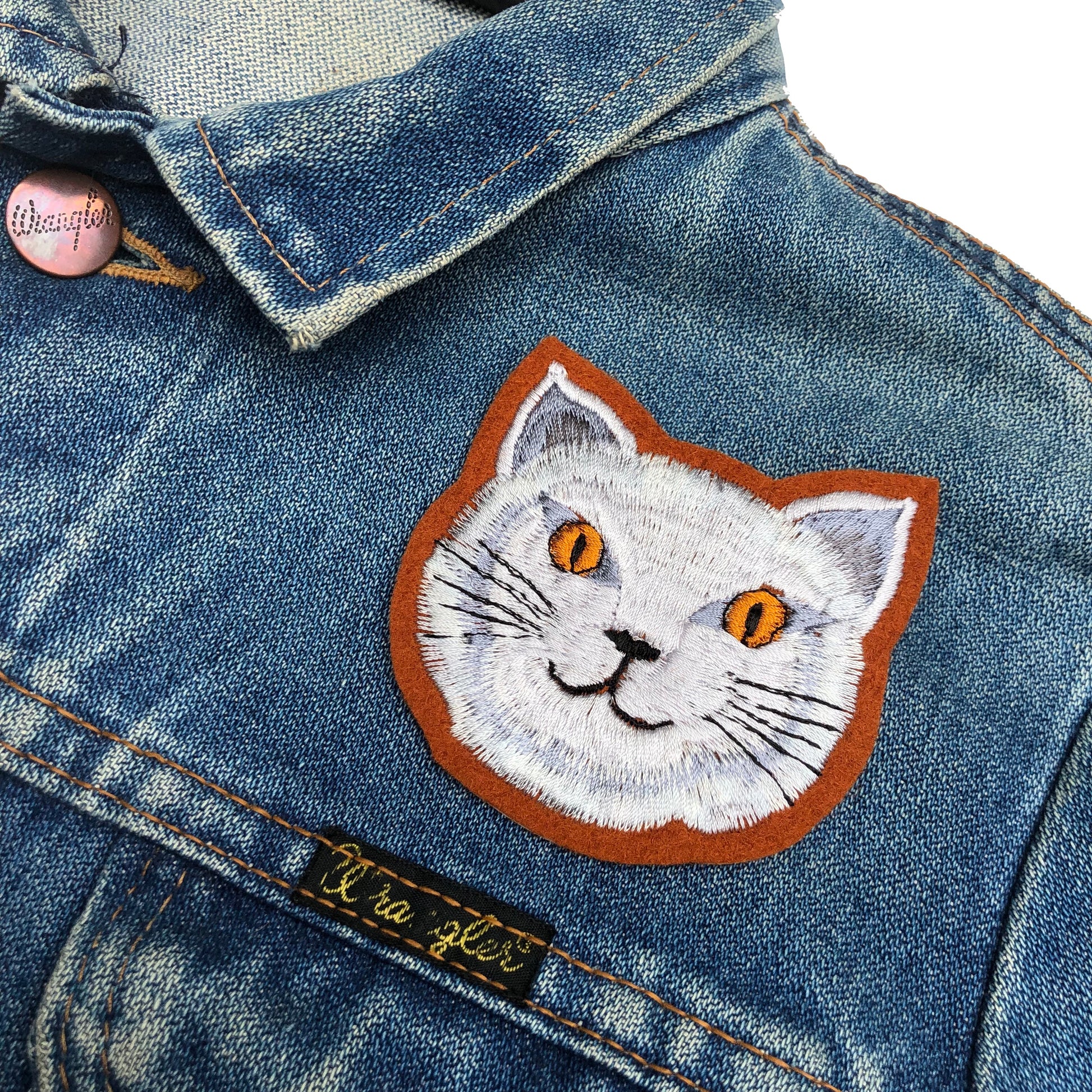 Close-up of fat cat embroidered patch on blue denim jacket