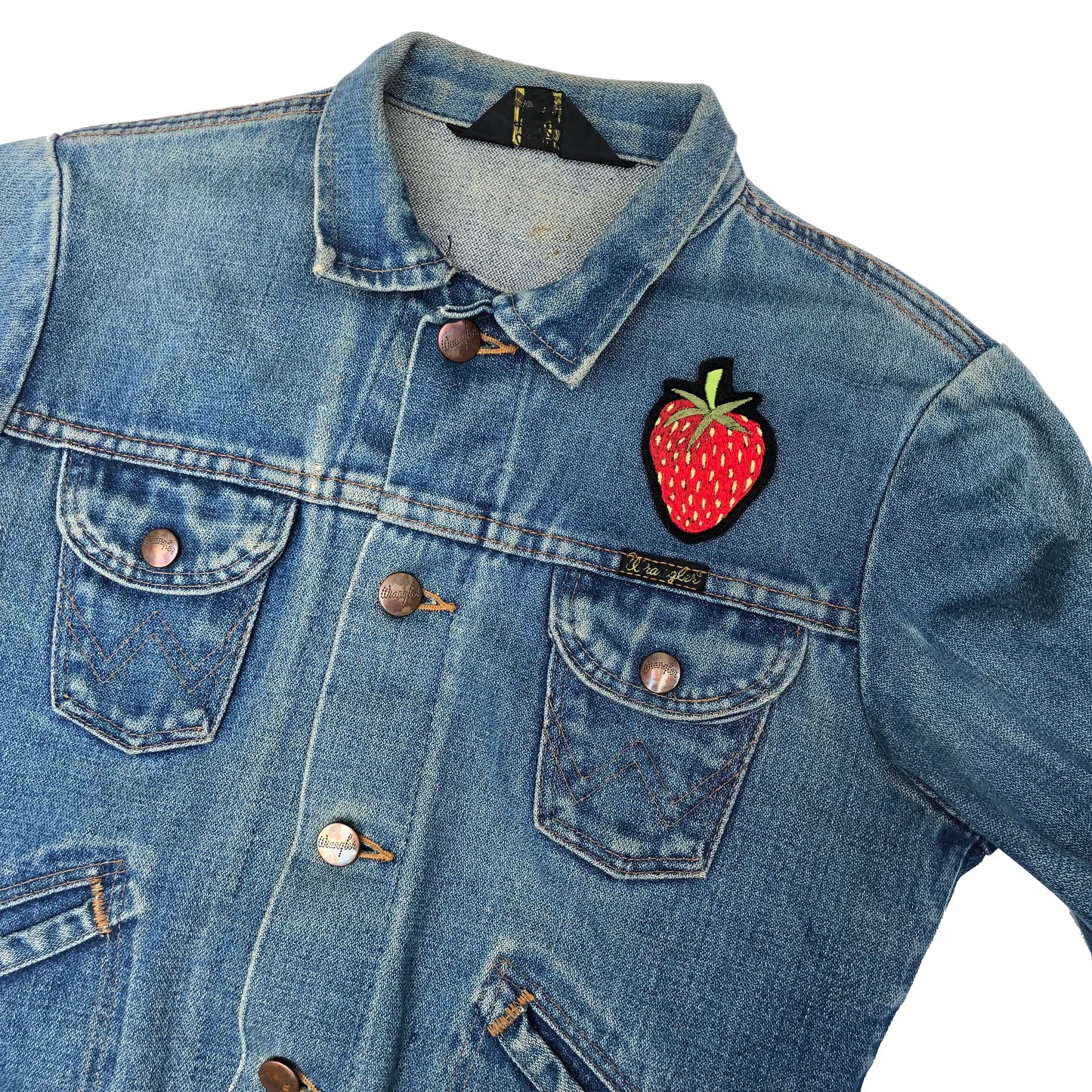 Strawberry embroidered patch on front shoulder of blue denim jacket