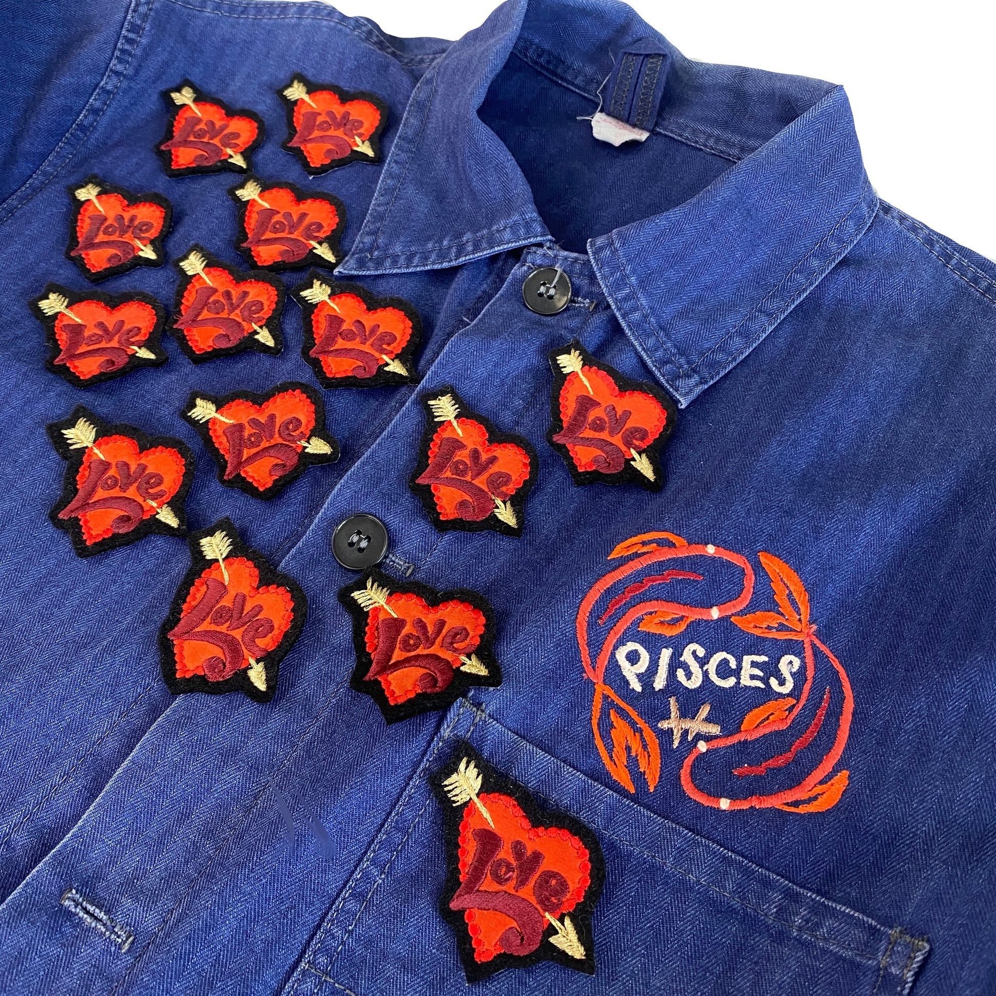 Mutiple tiny love embroidered patches shown scattered on front of blue jacket