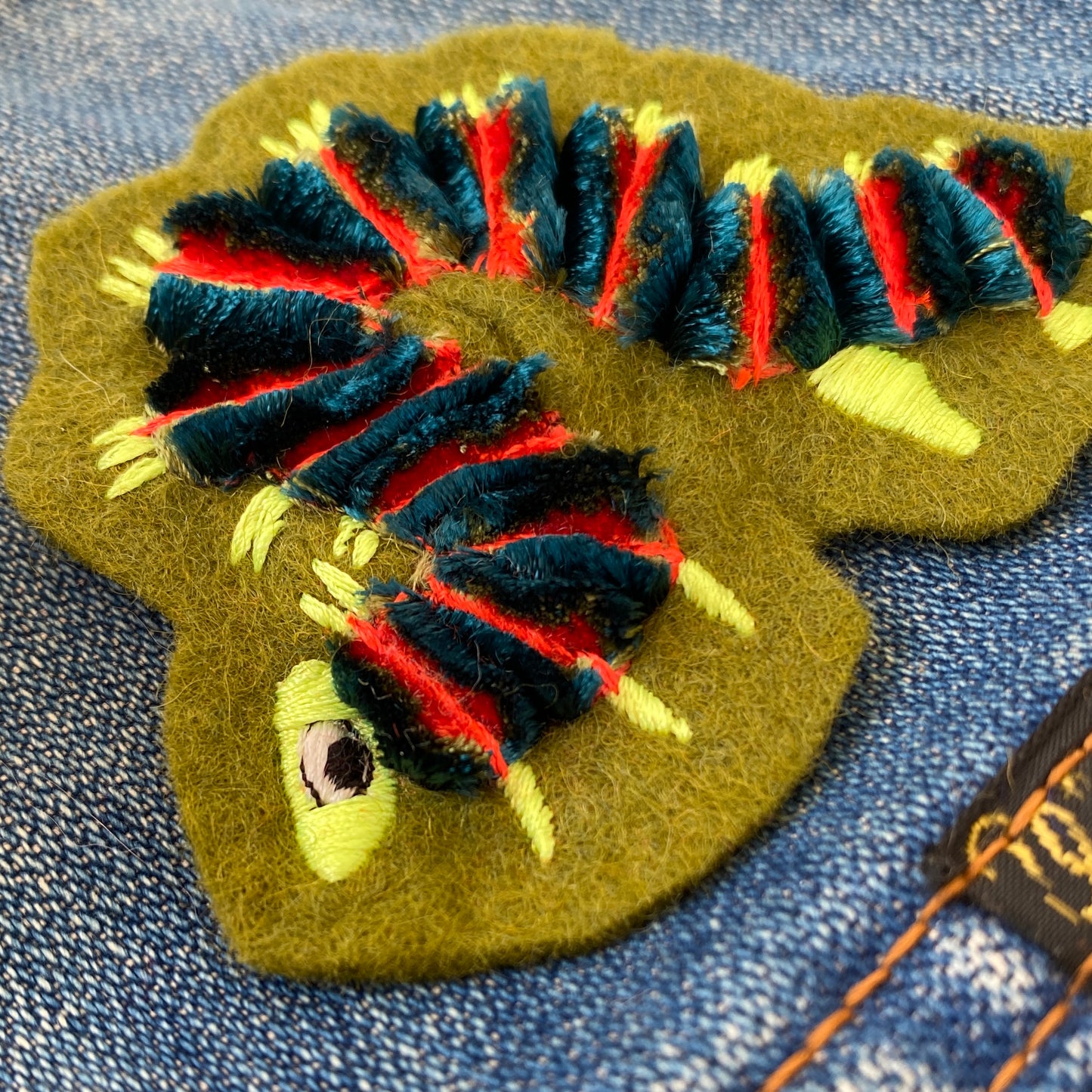 Close-up of fluffy caterpillar embroidered patch on denim jacket