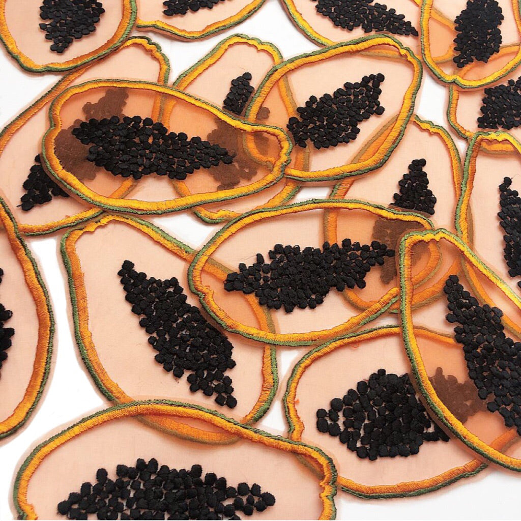 A number of sheer silk embroidered papayas scattered on a white background