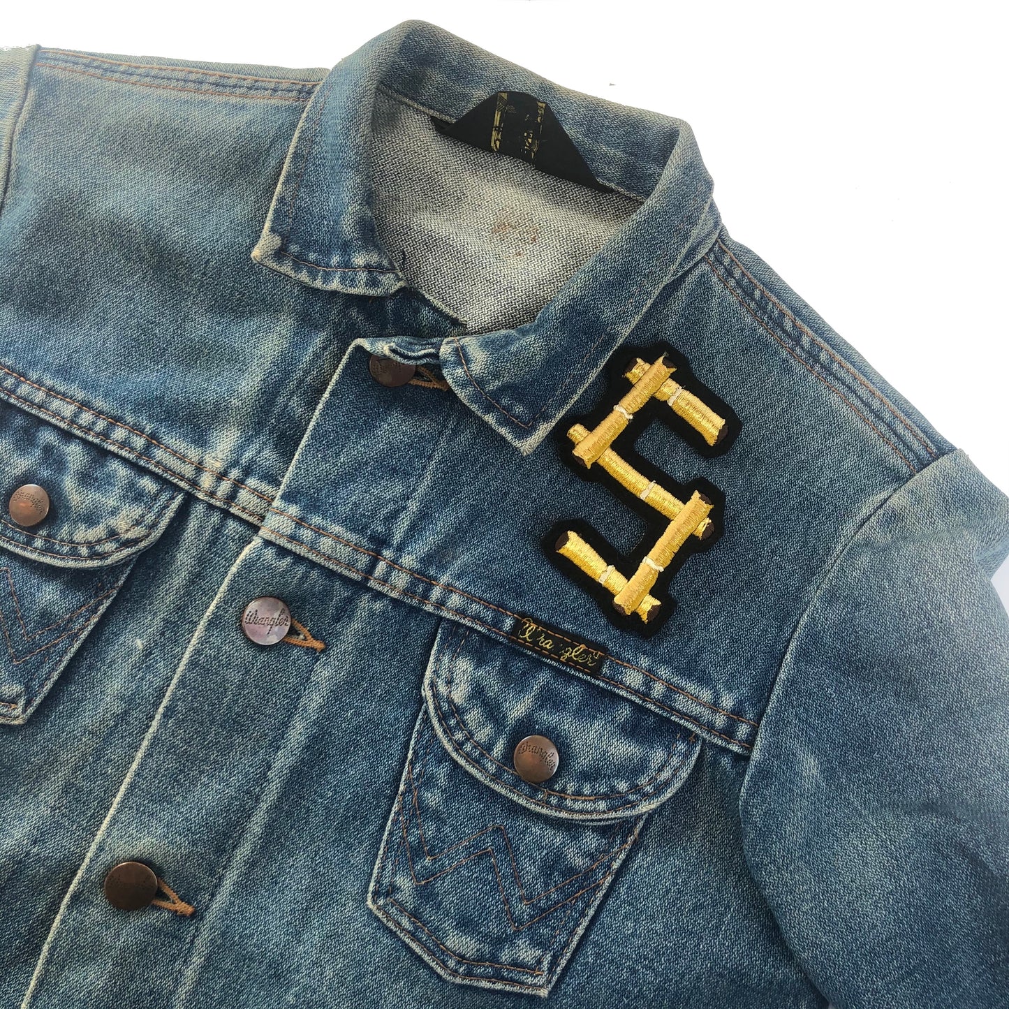 Bamboo embroidered letter S on the front shoulder of a blue denim jacket