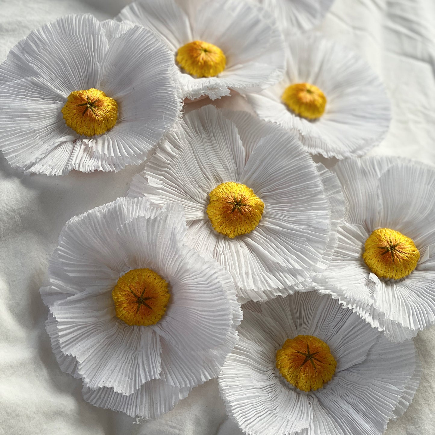 Collection of pleated fried egg flower embroideries on a white background