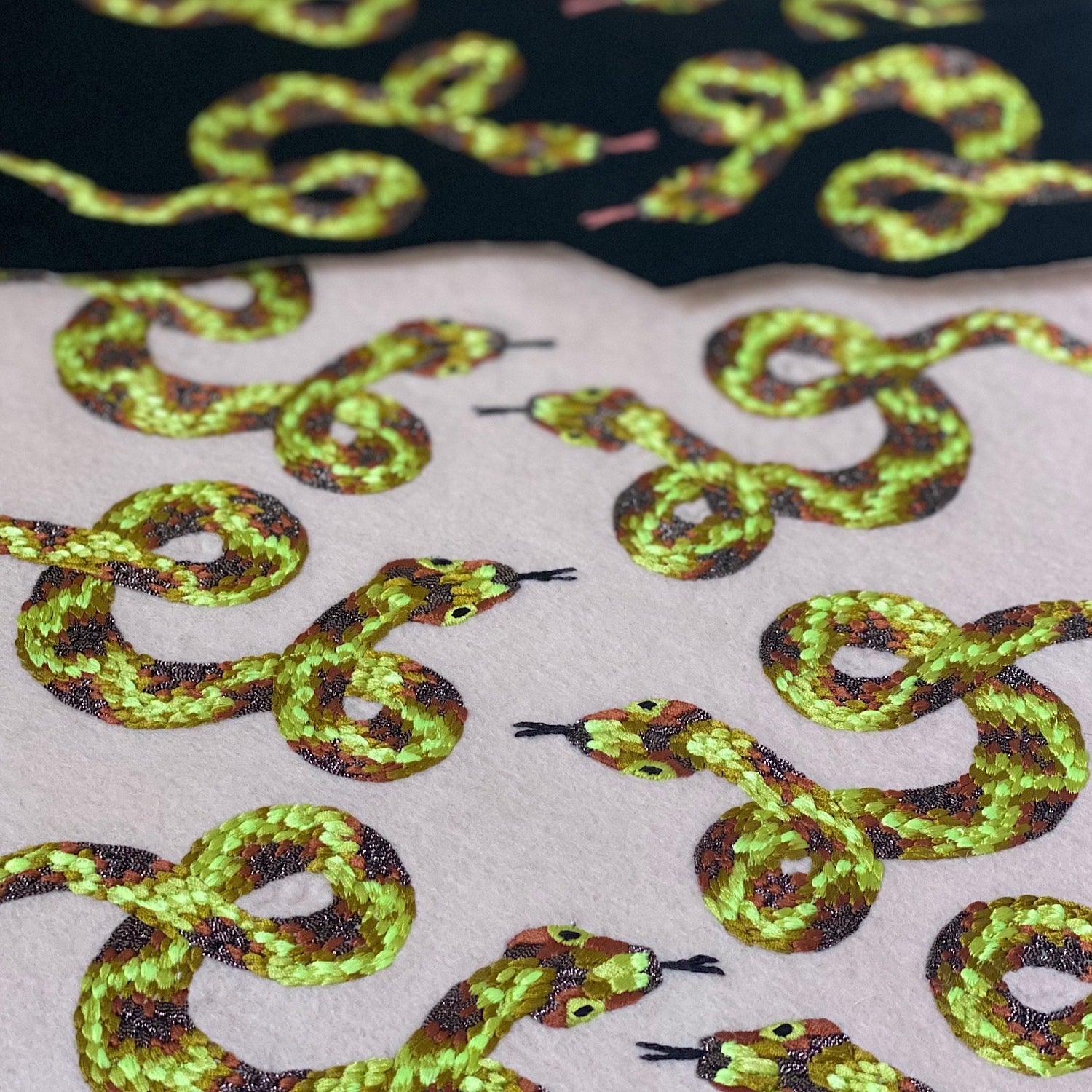 A number of uncut embroidered snake patches, some on black felt and some on cream felt