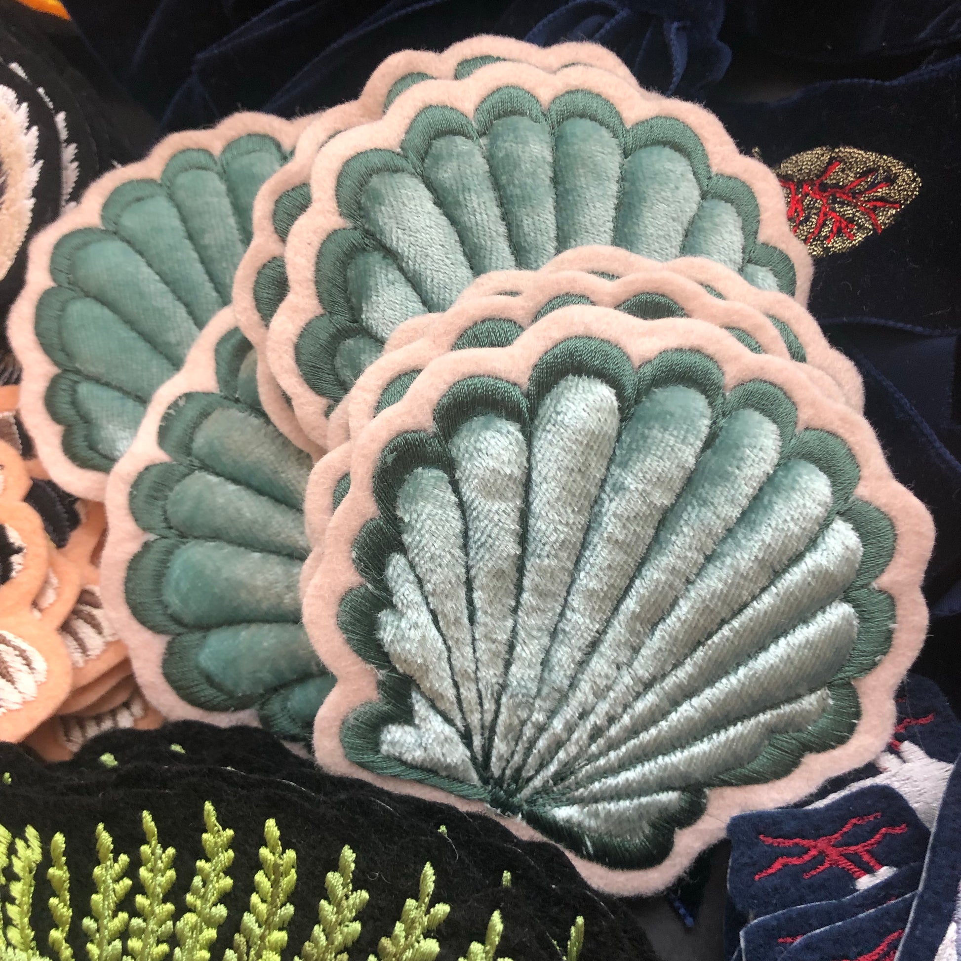 A stack of velvet padded shell patches with other Ellie Mac Embroidery patches seen in the background
