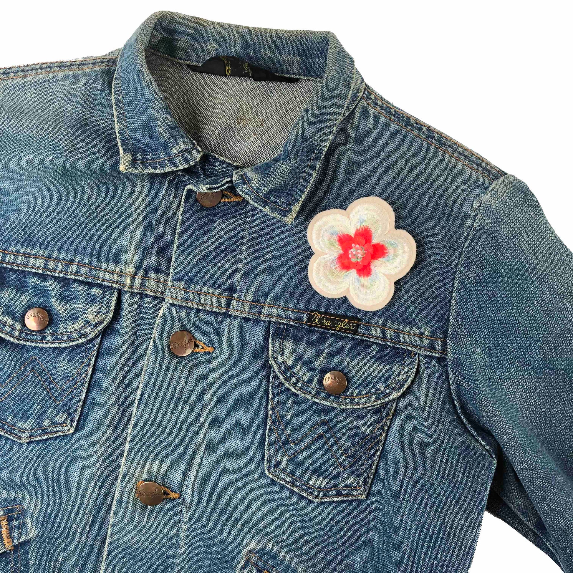 Embellished flower patch on front shoulder of a dark denim jacket