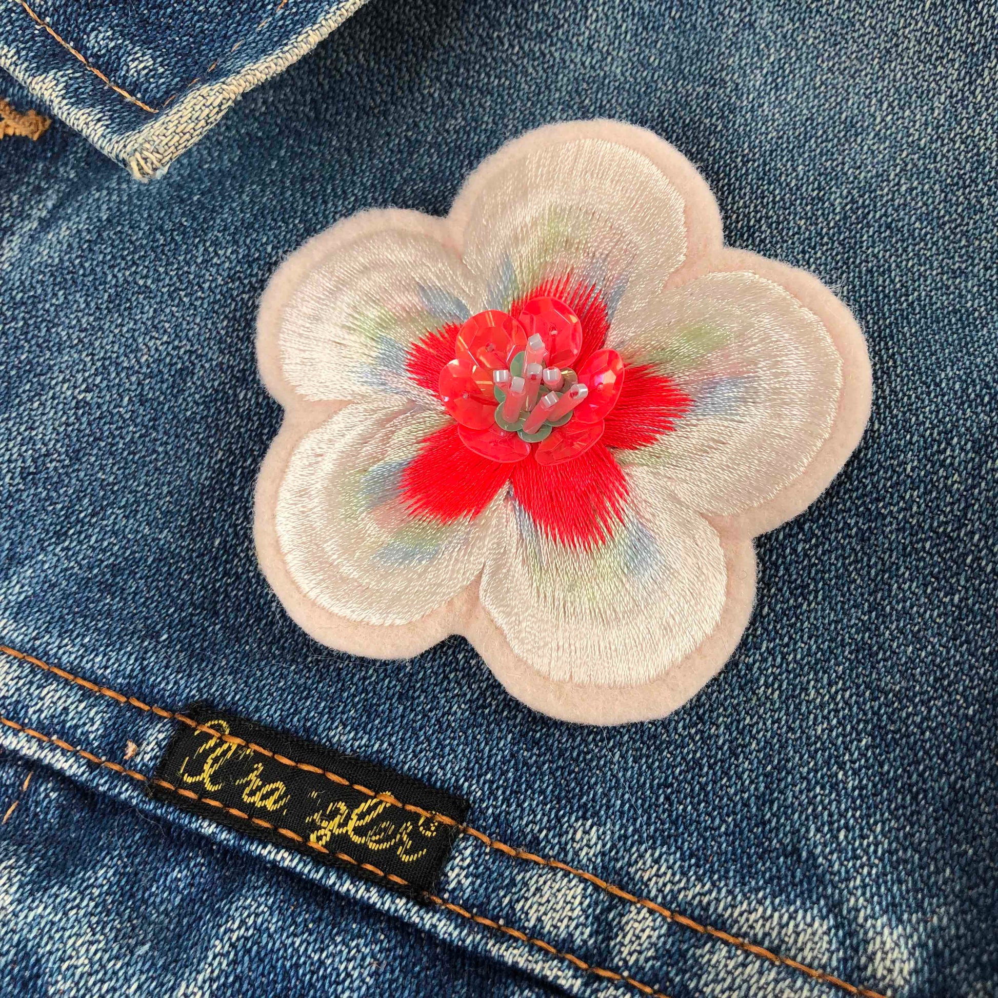 Close-up of embellished flower patch on dark denim jacket
