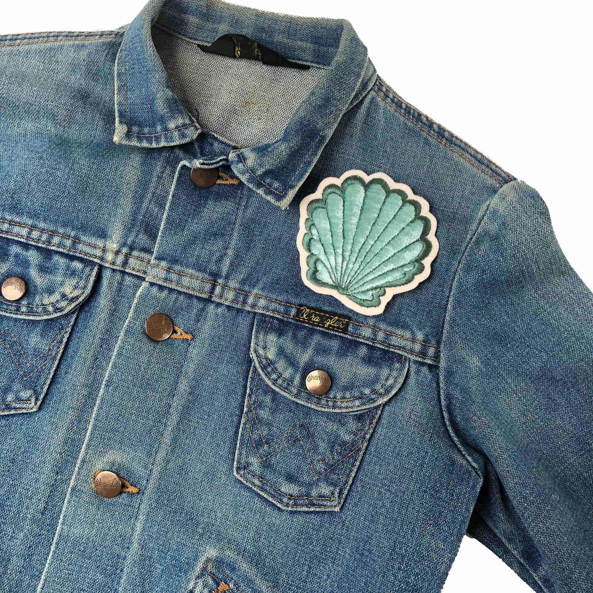 Velvet padded shell patch on the front shoulder of a dark blue denim jacket